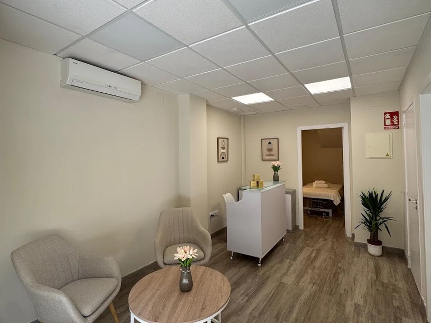 Recepción de Kore Restore con sillón, mesita con flores y suelo de madera